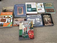 Photo of ten assorted books related to art pottery, antiques, and collectibles laid flat on a wooden surface.