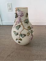 Full vase front view showing raised floral and leaf design with gold accents