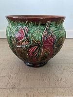 Front view of jardiniere showing detailed butterflies and foliage design with green and brown glaze.