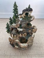 Full front view of the musical wolves scene figurine showing wolf figures on a rocky natural base with pine trees.