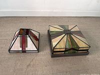 Two stained glass lighting pieces side by side on floor.