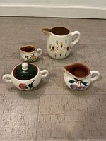 Four Stangl pottery pieces arranged on the floor showing all items and designs.