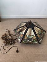 Full view of hexagonal stained glass Tiffany style pendant light fixture with metal chain and electrical cord attached.