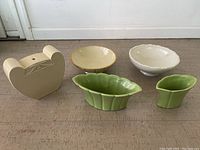 Lot of five Trenton Potteries ceramic items on floor. Beige pottery planter, green leaf-shaped bowls, and cream bowls.