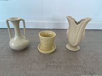 Three Trenton Potteries pieces: a narrow-neck double-handled vase, yellow planter with saucer, and petal-shaped vase