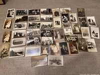 Overhead view showing approximately 45 vintage portrait postcards laid out, showcasing a mixture of individual and group portraits as well as some buildings and landscapes.