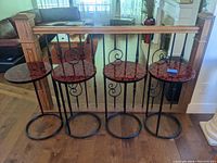 Four lacquered and steel side tables in a row showing the overall design and scale.