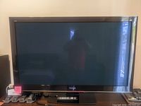 Front view of the 54 inch Panasonic plasma HDTV showing the screen and base with remote resting on the stand.