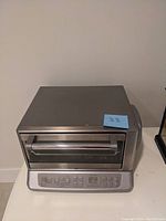 Front view of the Cuisinart toaster oven showing the stainless steel door, handle, and control panel with buttons and digital timer.