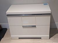 Front view of white lacquer side drawer unit with chrome handles and base.