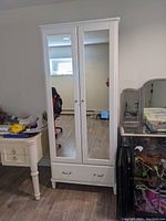 Front view of the white wardrobe with two mirrored doors and a drawer below.