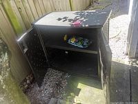Front angle showing the cabinet with doors open, revealing one shelf inside with a bag and small item placed on the shelf.