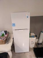 Front view of small white refrigerator with freezer compartment on top showing exterior condition.