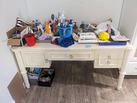 Front view of the white wooden desk with three drawers and various items on top