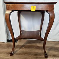 Side view showing the table's elegant curved legs and claw feet, along with the lower shelf connecting the legs.