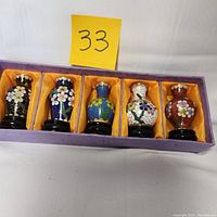 Full front view of five cloisonne enamel bud vases arranged side by side in purple box with orange lining and black bases, numbered 33