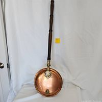 Full view of the copper and brass bedwarmer showing wooden handle and pan.