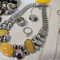 Close-up photo detailing Lia Sophia necklace with yellow stones and three rings