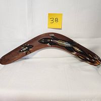 Photo of full length of boomerang showing overall shape, wood grain, and painted Aboriginal design.