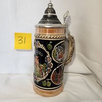 Side view of lidded beer stein showing Heidelberg city scene on cobalt blue and tan lustre background with floral details.