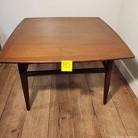 Front view of square wooden coffee table showing tapered legs and horizontal support beam.