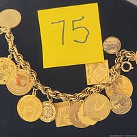 Photo showing the full charm bracelet laid flat with a close-up on the gold-filled and sterling silver charms featuring various destination-themed designs.