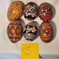 Top view of all six wooden Easter eggs showing detailed folk art designs and color variety