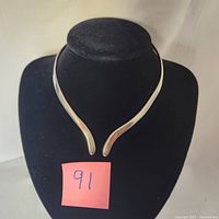 Front view of the vintage Mexican silver collar necklace displayed on a black jewelry bust, showing the open ends and polished surface.