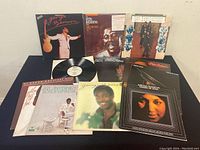 Photo showing the full lot display of 12 vintage soul and R&B vinyl records laid out on a table. Includes George Benson, Otis Redding, The Temptations, Al Green, Aretha Franklin, and more.