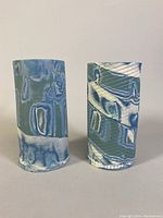 Two Bernie Zaharik 'ZZ' porcelain vases shown front view on a plain background, highlighting the swirling blue and white glazed design on cylindrical forms.