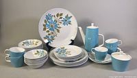 Full set displayed showing coffee pot, sugar bowl, plates, bowls, teacups, and saucers with blue and olive floral design.