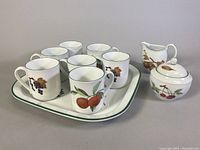 Full view of the set showing 7 mugs on the square plate and the sugar bowl with creamer next to it.