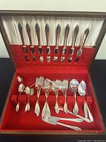 Full lot with knives in lid and other pieces arranged on red velvet