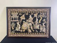 Full view of the framed tapestry showing the entire scene with figures and elephant in black background and gold embroidered border.