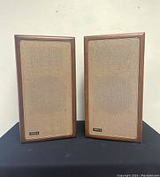 Pair of speakers with cloth grills attached on black surface