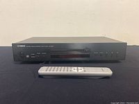 Front view of black Yamaha CD-S300 CD player with remote placed in front.