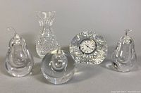 Full view of all five items: three Kosta Boda blown glass perfume bottles, one Waterford crystal mantle clock, one clear glass bud vase.