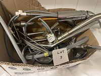 Box containing chrome faucets, flexible hoses, and metal pipes