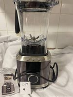 Front view of Paderno high-speed blender showing clear jar with stainless steel blades on motor base with control dial and buttons, power cord wrapped around base, and small lot sign.