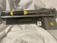 Heavy-duty metal Brutus tile cutter with black base and yellow adjustment knob, black and yellow handle on guide rails.