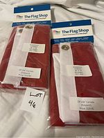 Two unopened Canadian flags made of polyknit, 18x36 inches, with tag showing brand The Flag Shop and price $19.95 each.