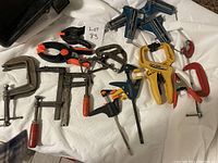 Overview of assorted clamps on a white cloth surface