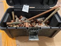 Black plastic toolbox open showing many copper plumbing fittings and copper bars inside