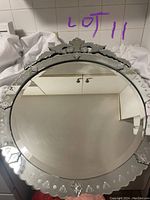 Full view of the round decorated wall mirror showing the etched glass border and ornamental design at top.