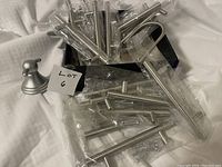Silver drawer pulls and knob sealed in clear plastic on white surface with seller's lot card visible.