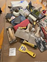 Front view of most tools and supplies showing trowels, putty knives, sanding blocks, mesh tape, and compound bottles in metal tray