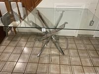 Full view of rectangular glass top dining table with polished metal base showing the table top and base structure.