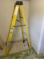Full view of yellow aluminum step ladder with black top cap, Werner branding visible on side.