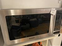 Front view of Panasonic stainless steel microwave oven with control panel and glass window on door.