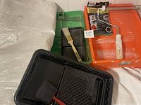 Photo showing paint trays, brushes, roller, plastic sheet, gloves package